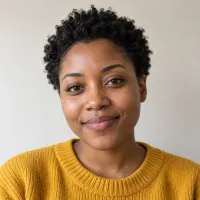 Portrait of a woman with short hair in a mustard-yellow sweater.