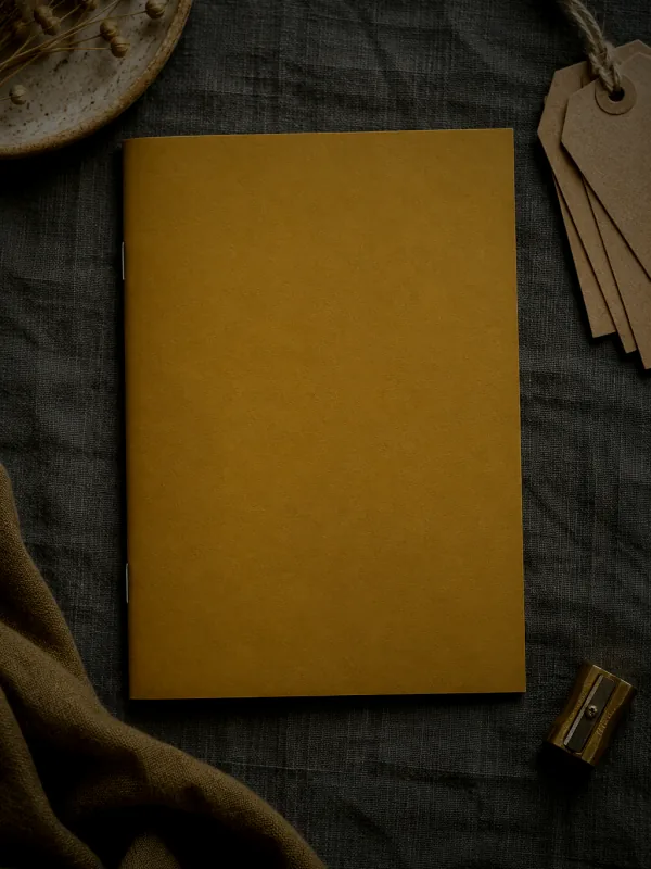 La couverture de « Mon guide pour fixer tes prix » : un livret ocre posé sur un lin gris, entre des étiquettes en kraft et un taille-crayon en laiton