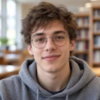 Portrait of a young man with round glasses in a grey hoodie in a library.